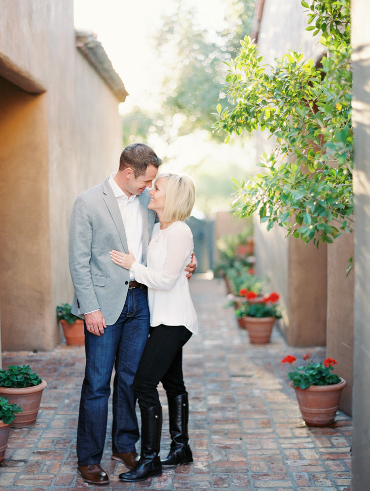 Fashionable couple smile together in outdoor courtyard. Phoenix engagement shoot. 