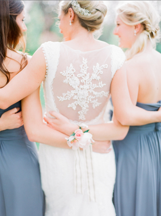 Elegant lace back wedding dress with bridesmaids in pale blue dresses.