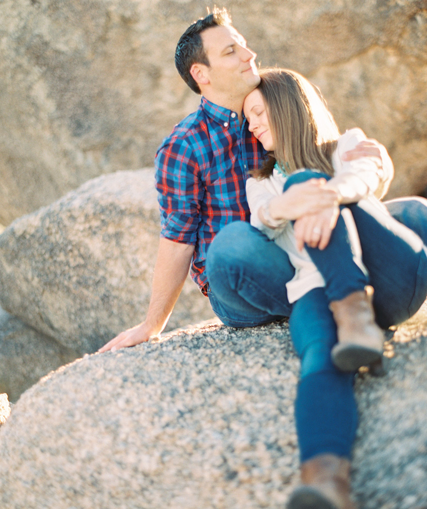 Sun-kissed cuddle on the Arizona boulders. Outdoor engagement shoot with quiet romance.