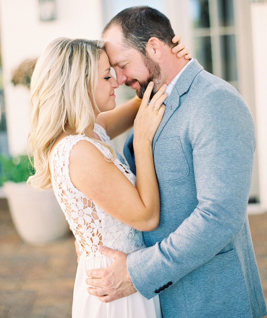 Sweet, romantic body language as a couple embrace in front of their Arizona home. Engagement shoot.