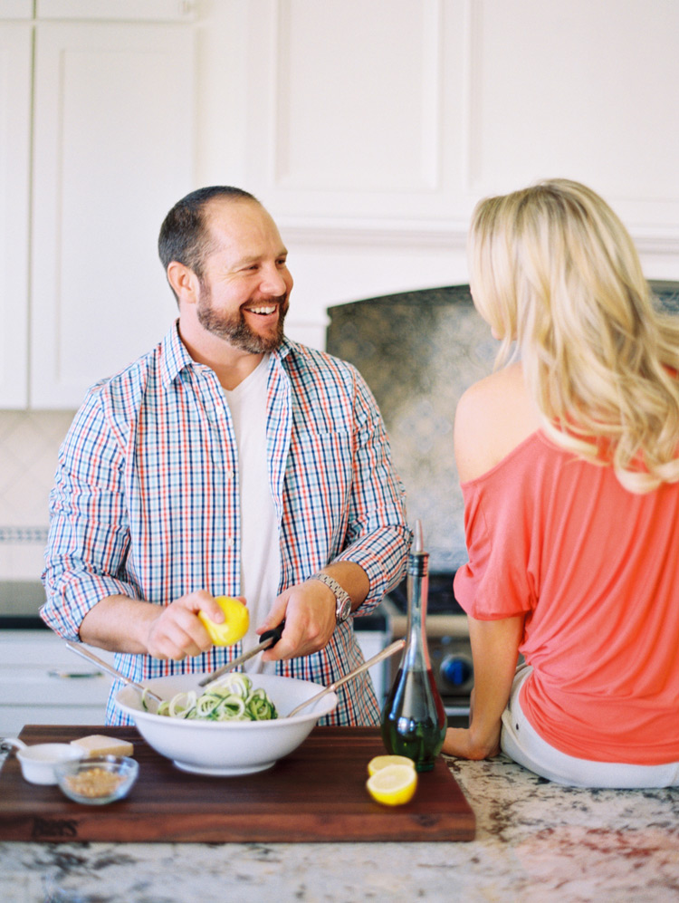 Laughing and cooking together in their beautiful kitchen. Domestic engagement shoot ideas. 