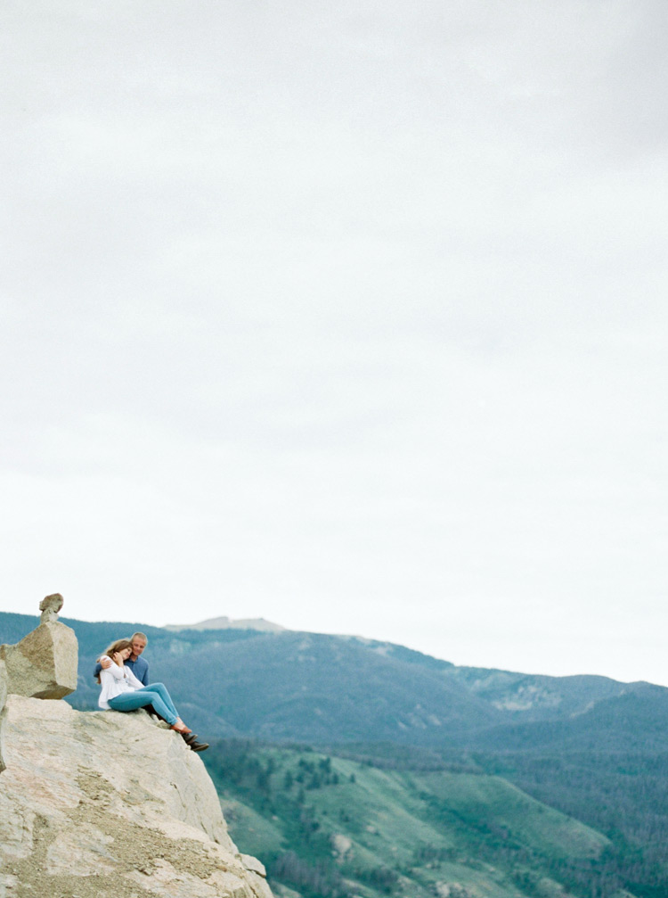 Couple sitting cliffside in Colorado mountains photo shoot