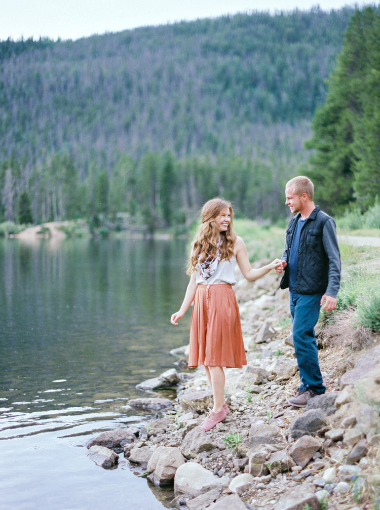 Bride looks back at fiancé near lake in Colorado