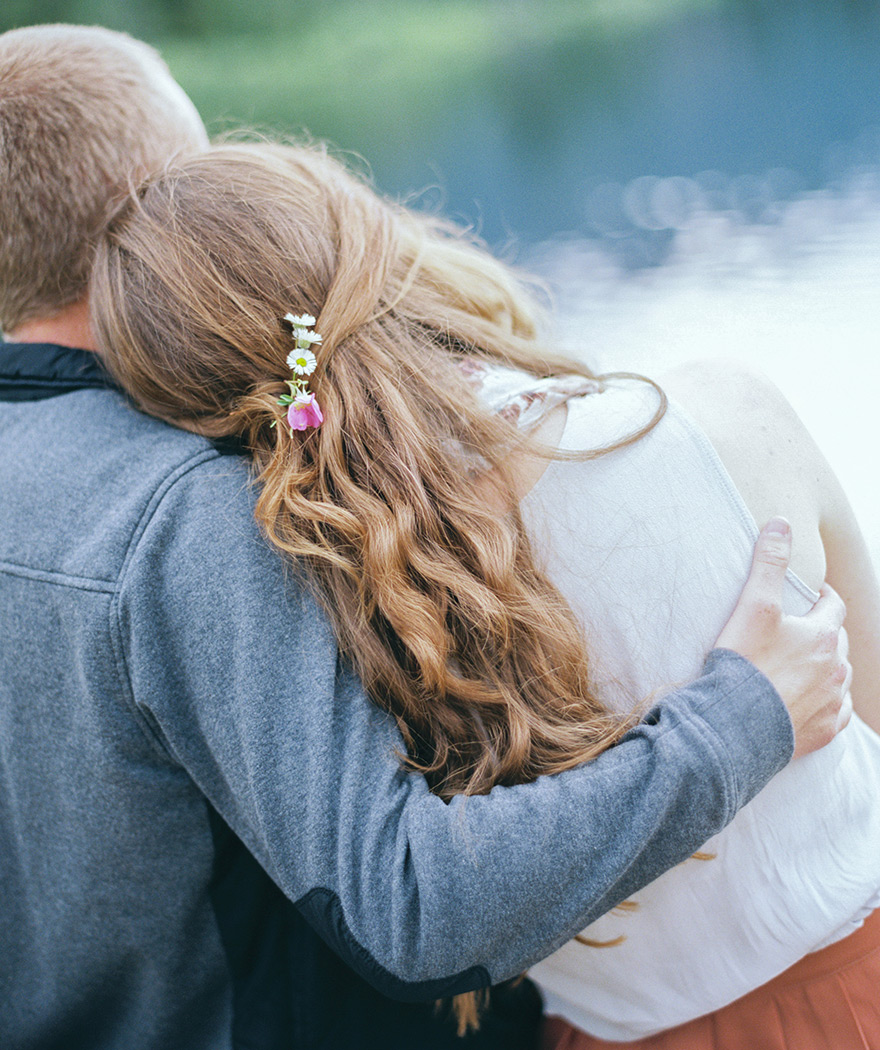 Wildflowers in hair as groom cuddles beautiful fiancé Rocky, Colorado session