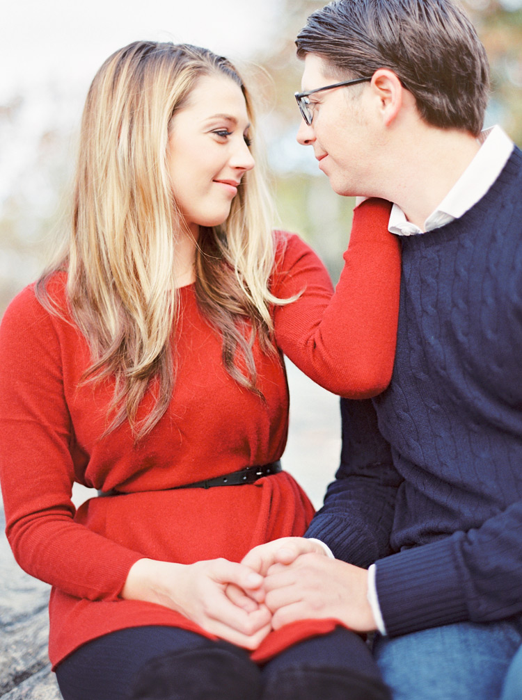 Tender moment between a loving couple with clasped hands. Engagement shoot posing. 