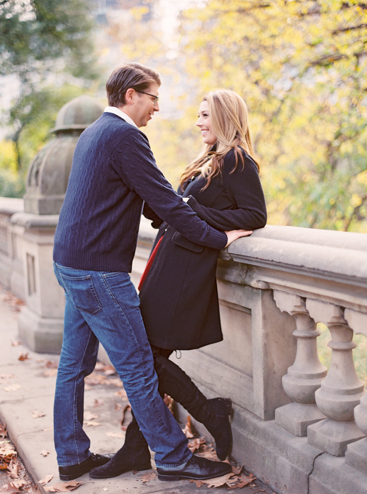 Leaning against the railing of a bride in Central Park. Autumn engagement shoot style in NYC.