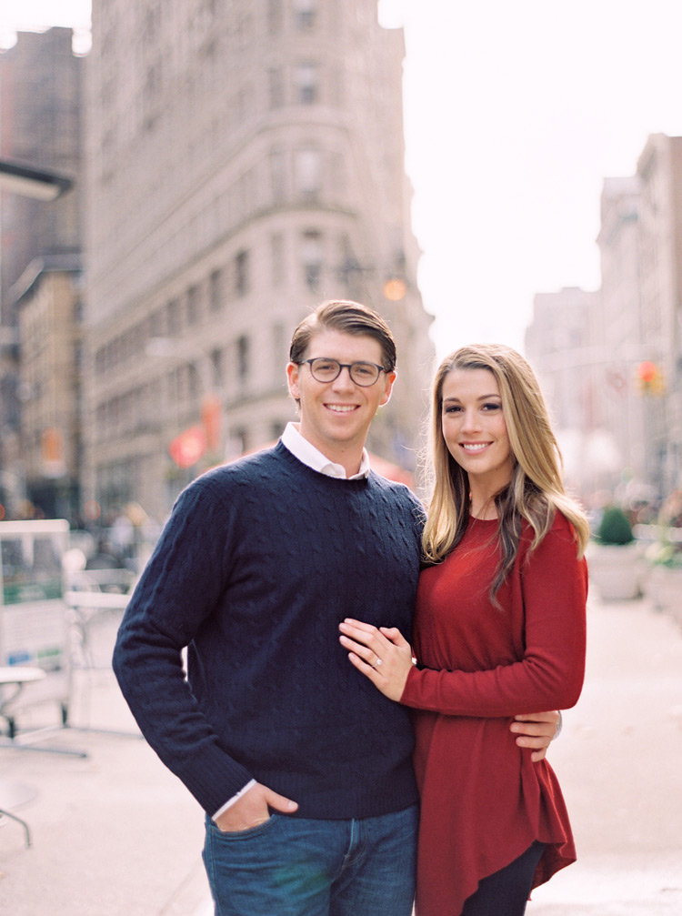 Smiling couple in front of New York's Flatiron Building. NYC engagement shoot. 
