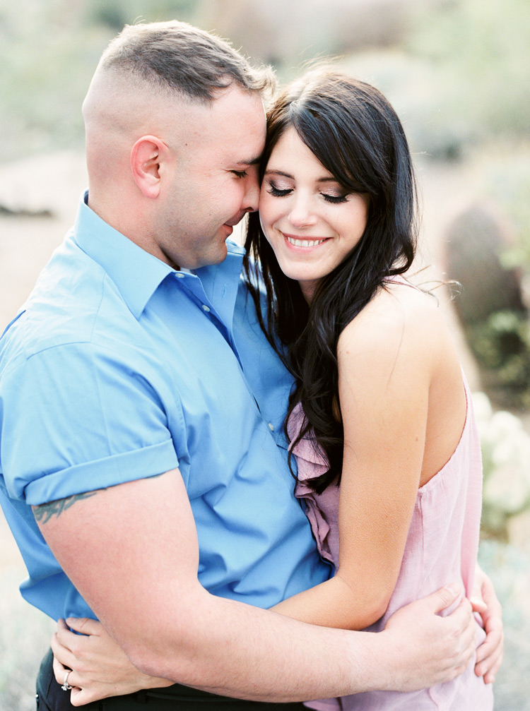 A happy couple nuzzle together during their outdoor engagement shoot. Long dark hair & gorgeous grin