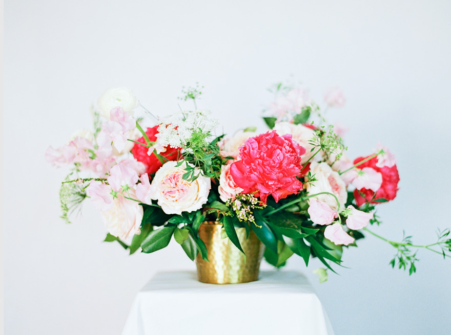 Loose, organic flower design in shades of pink in a low brass basket.