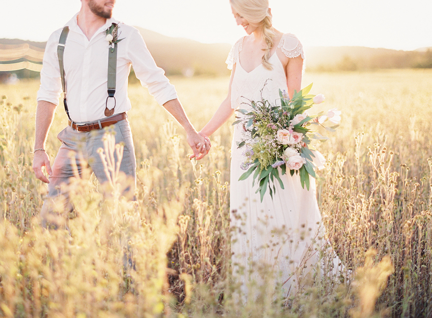 Natural fields session with bouquet for bride and groom holding hands 