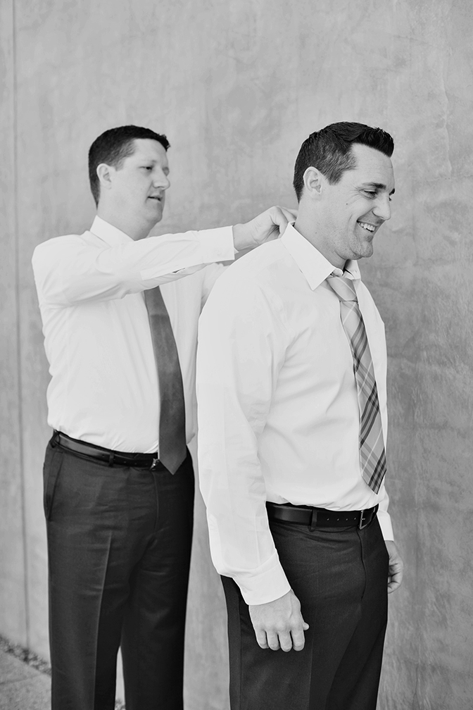 Best man helps the groom with his tie.