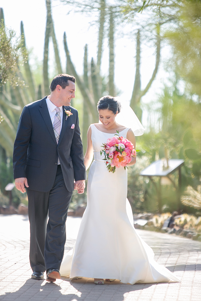 Bride & groom walk hand in hand. Pink wedding bouquet.