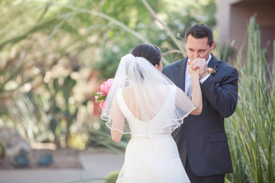 Groom kisses his bride's hand at their first look before the wedding.