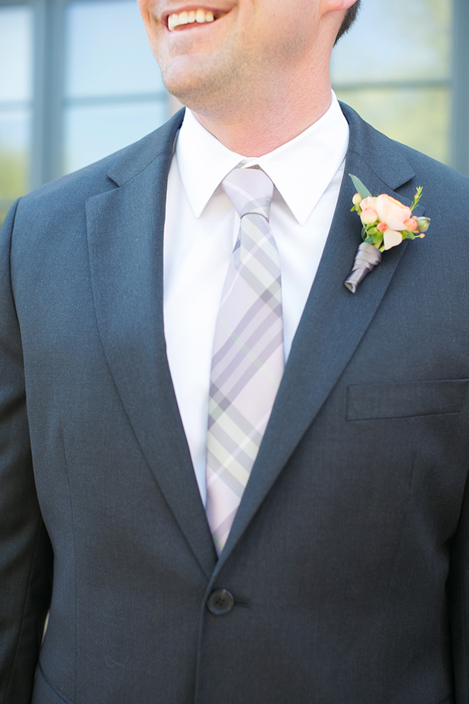 Casual wedding groom style with a plaid tie and a sweet boutonniere.