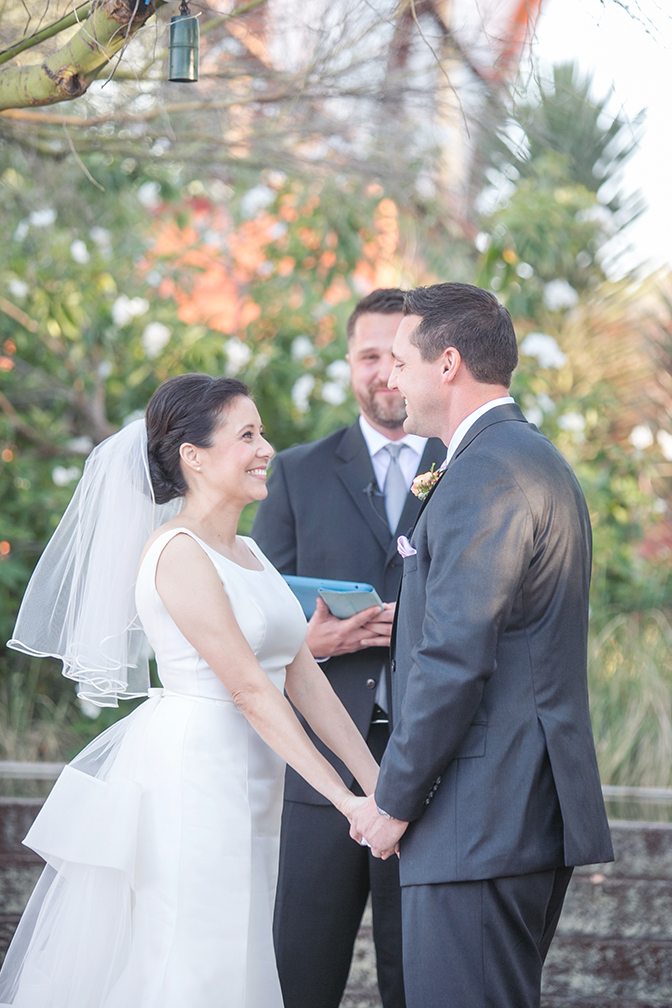 Bride & groom grin as they say their vows. Outdoor wedding ceremony.