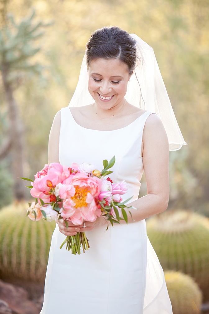 Happy bride with a bouquet of loose pink flowers.