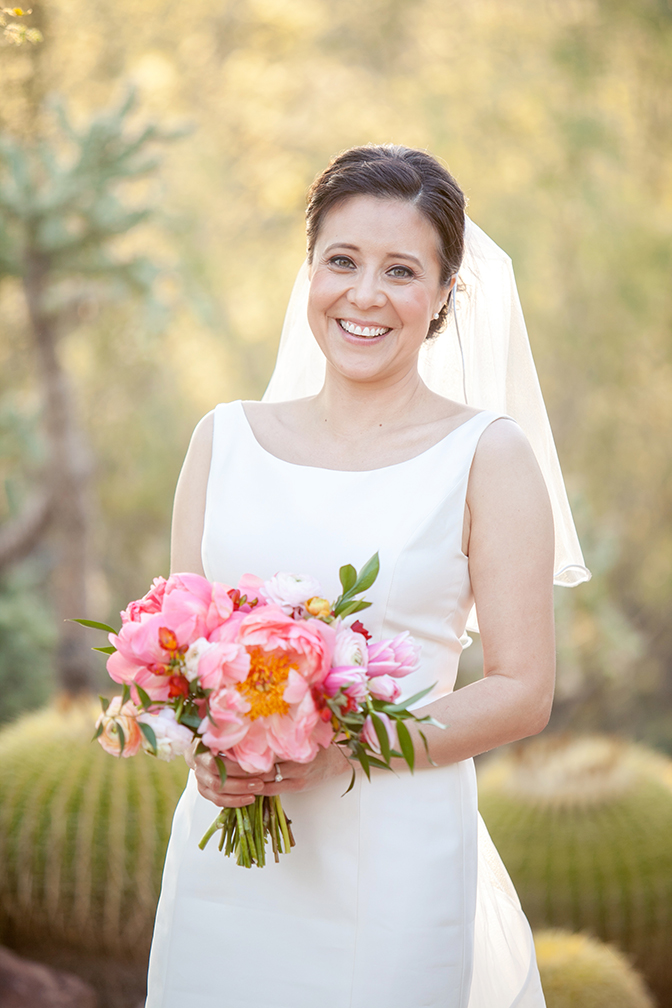 Smiling bride with a bouquet of loose pink flowers.