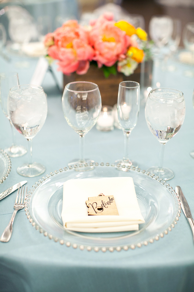 Pretty place setting with glass charger and unique wooden place card. Wedding reception style.