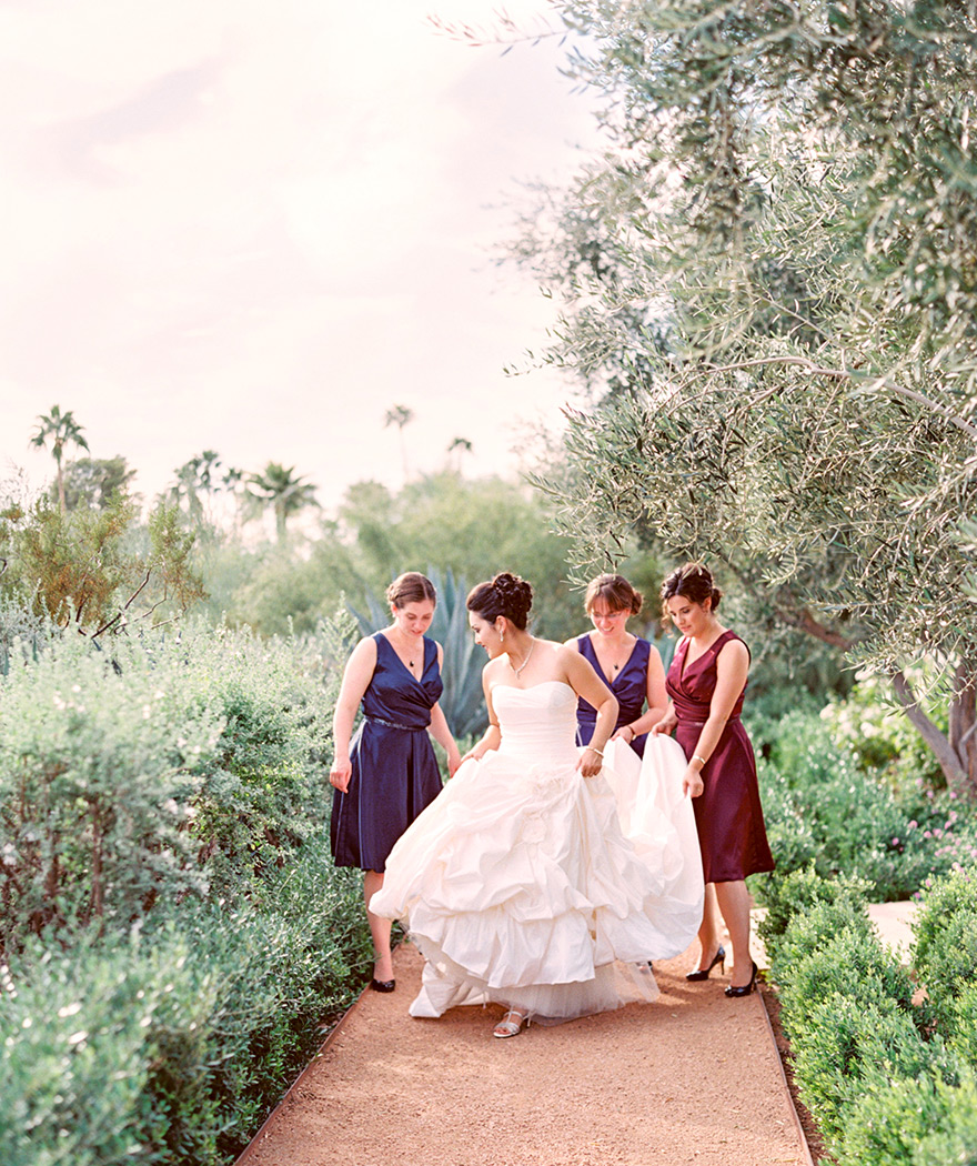 Bridesmaids help bride with her wedding dress at desert wedding at El Chorro in Paradise Valley, AZ.