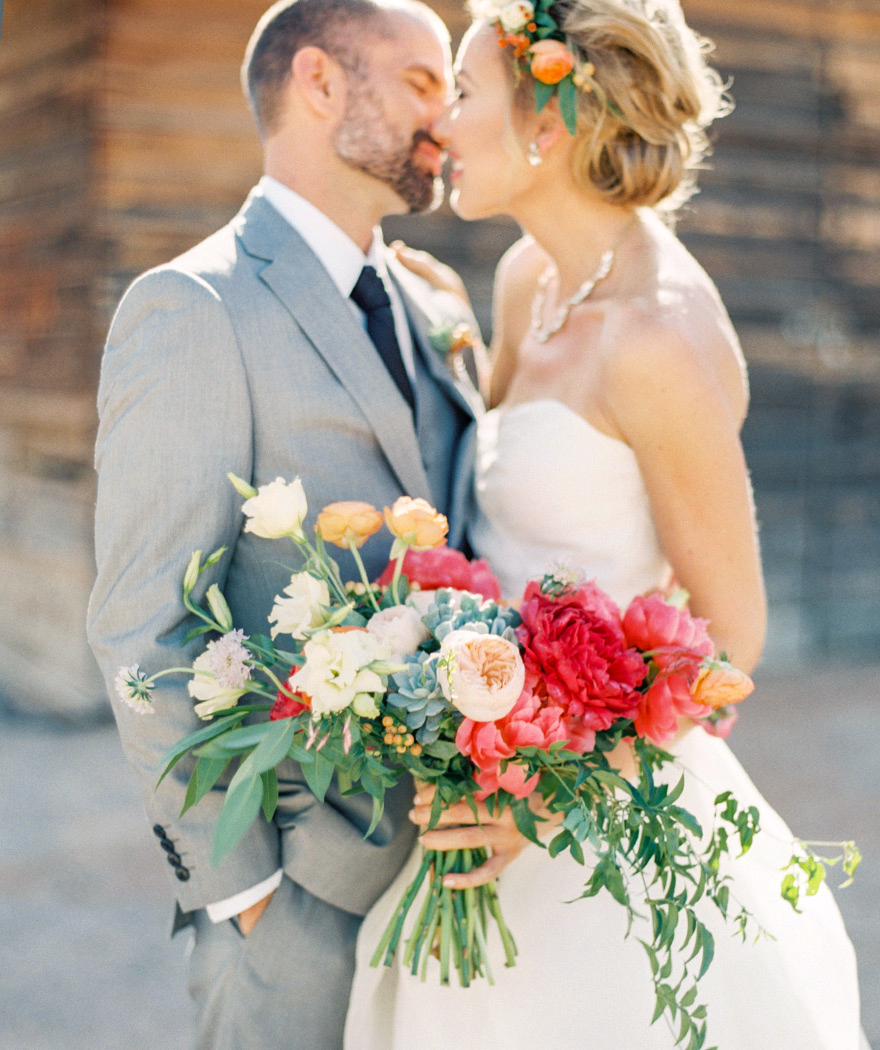 Bride and groom kissing on their destination ranch wedding. Beautiful bright pink bridal bouquet. 