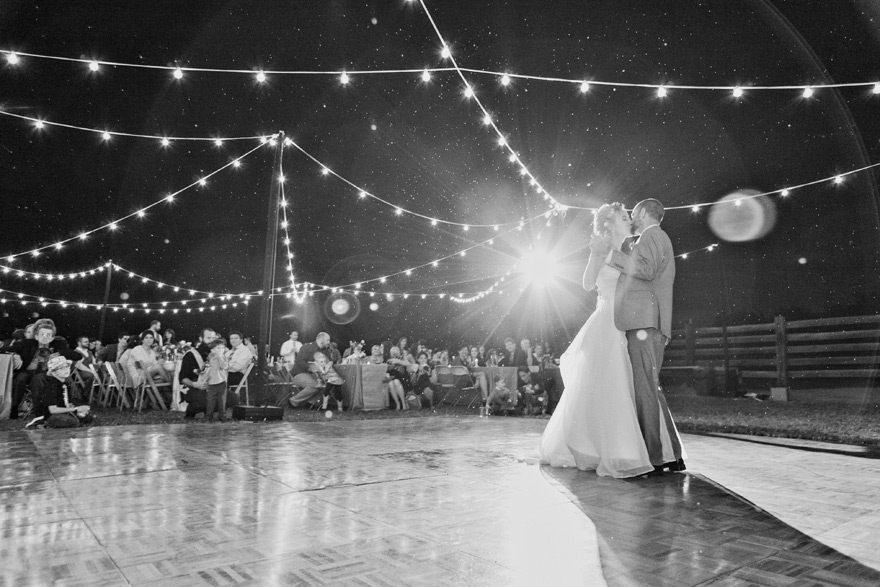 Bride and groom's first dance at wedding reception under string lights. Outdoor reception ideas. 