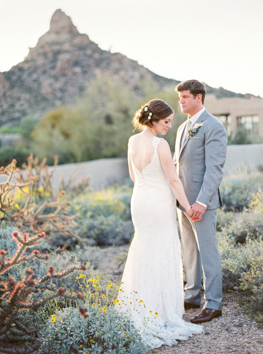 Bride and groom in the Arizona desert with mountain backdrop. Venue is Sassi for destination wedding