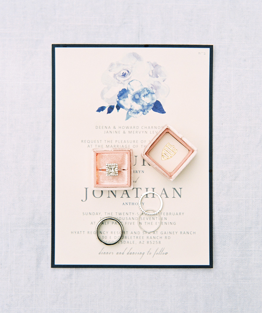 dazzling square engagement ring atop an invitation with watercolor touches