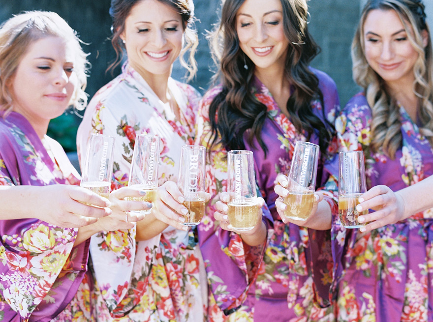 bridesmaids in floral robes toast with champagne