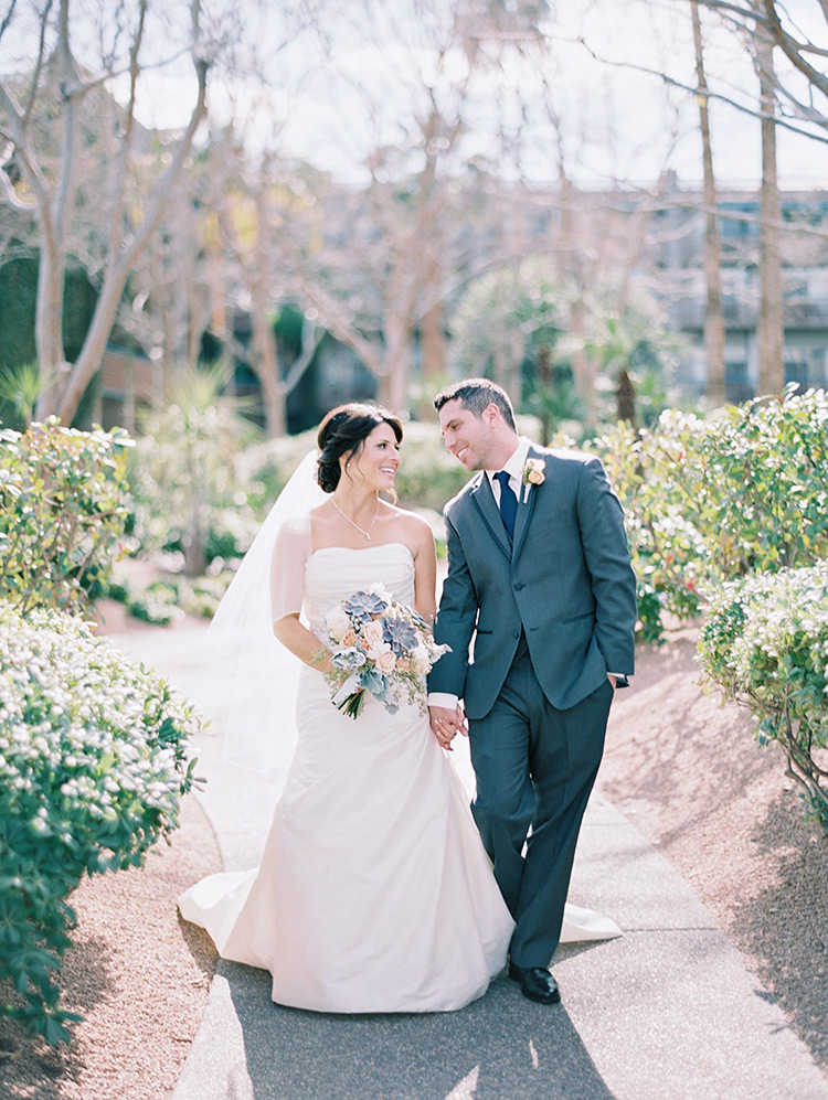 happy bride & groom walk hand-in-hand at Hyatt Scottsdale