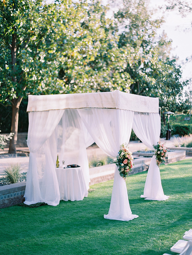 chuppah with fresh flowers, topped by a custom quilt
