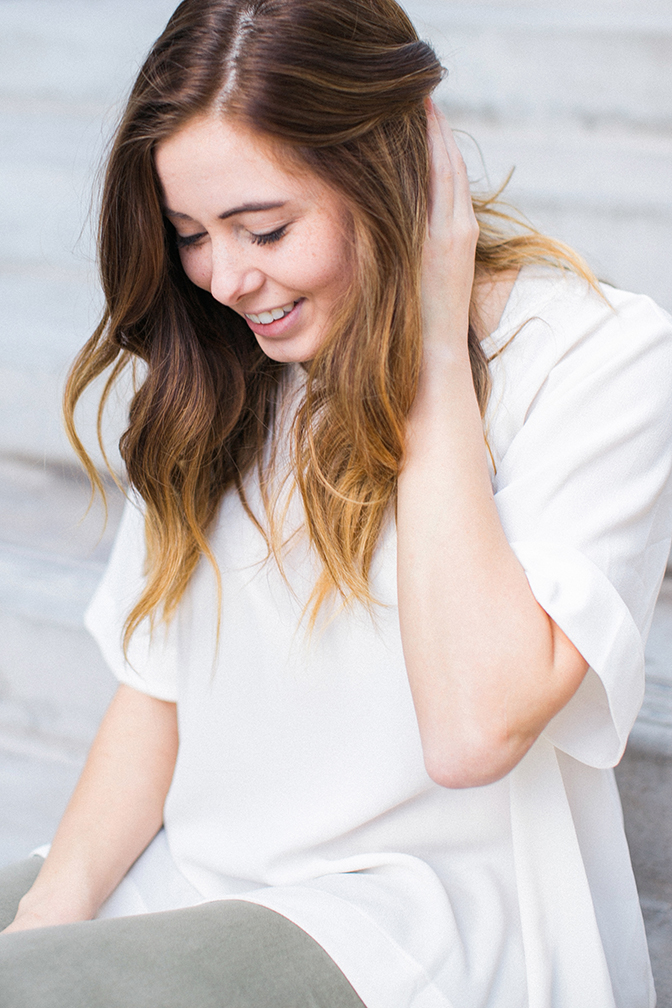 Casual moment of chic girl pulling hair back. Sitting on steps photo shoot. 