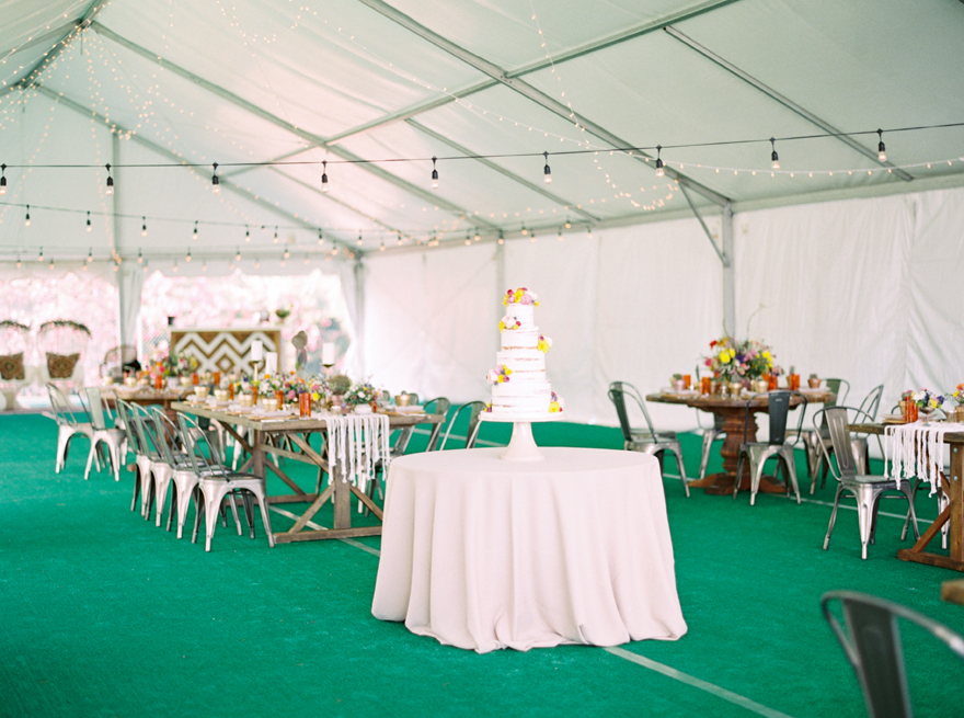 Nearly naked cake decorated with vibrant flowers at a boho reception
