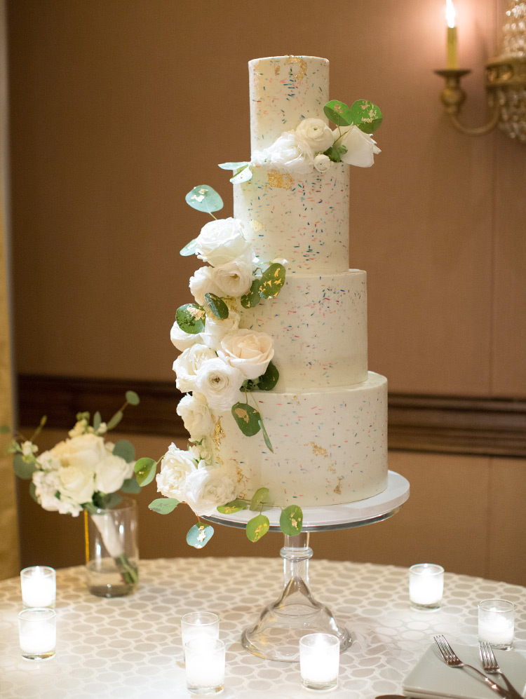 fun four-tiered wedding cake with sprinkles and roses