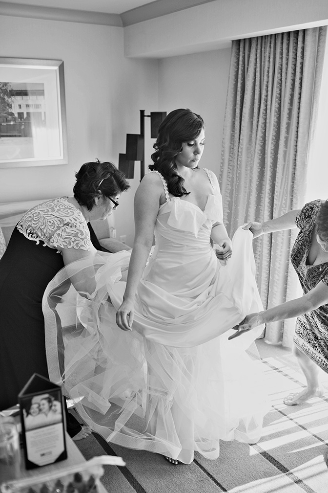 helping the bride into her dress