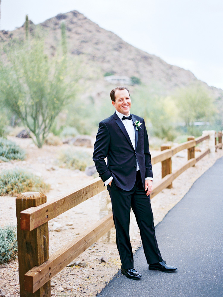 Smiling groom in a classic black tux. Desert wedding