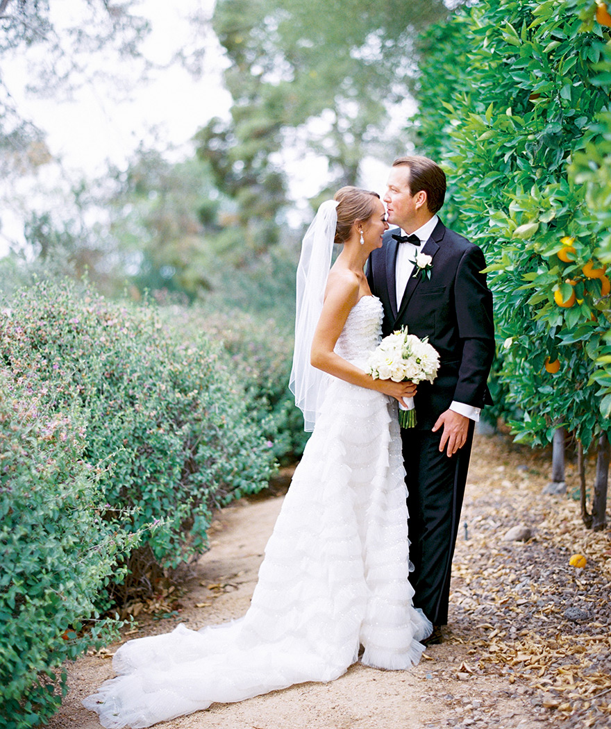Bride & groom embrace beside an orange grove. Arizona wedding
