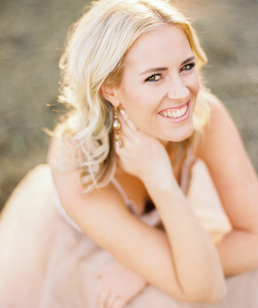 Beautiful perched blonde smiles in natural outdoor photo shoot. 