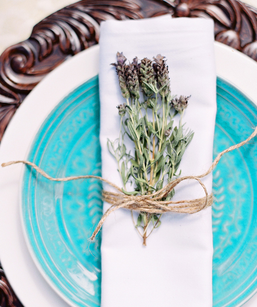 Place setting of carved wood charger, bright turquoise plate and dried lavender