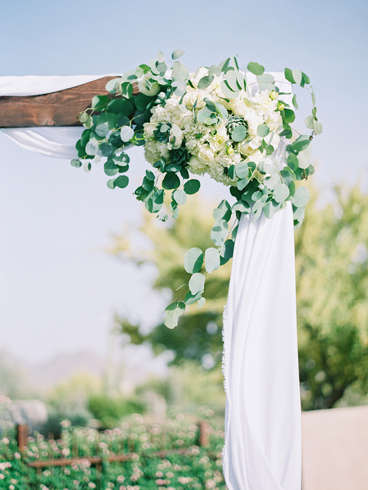 white flowers and fresh greens on a wedding arbor