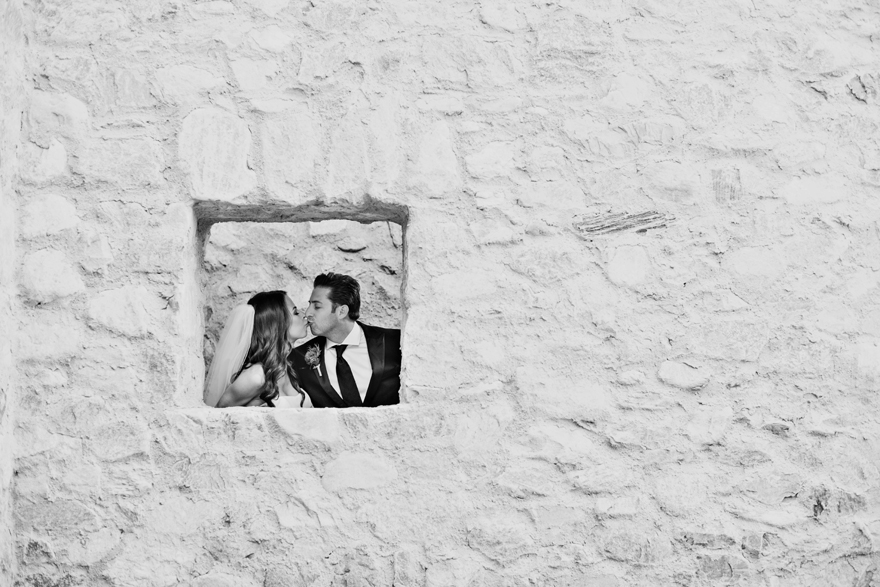 Bride and groom seen through the window in a stone wall. Silverleaf