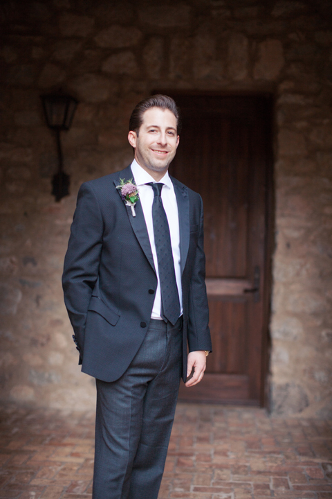 Happy groom in a navy suit with long tie and boutonniere
