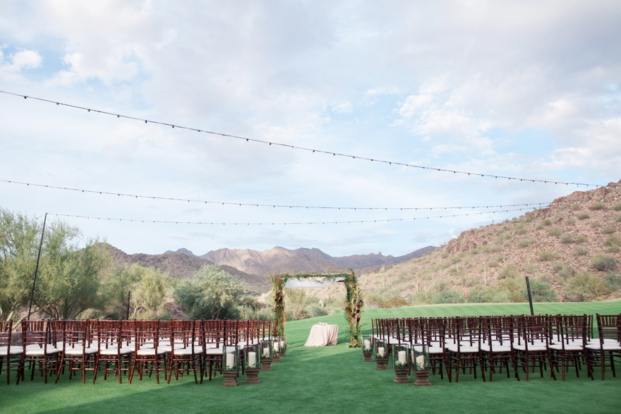 Outdoor wedding ceremony with a draped chuppa and wooden chairs. Arizona wedding