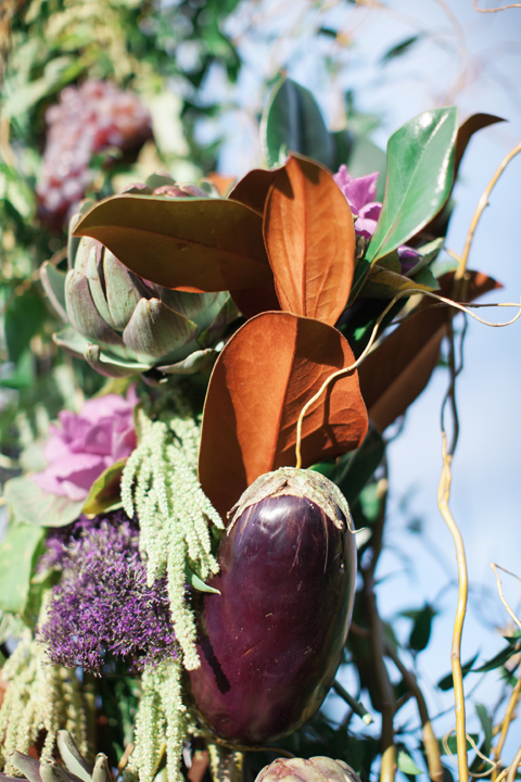 Eggplant, kale, magnolia leaves, and flowers decorate the chuppa
