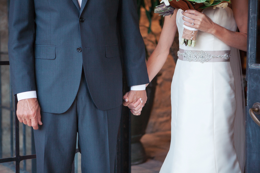 Bride clasps her father's hand before he escorts her down the aisle.
