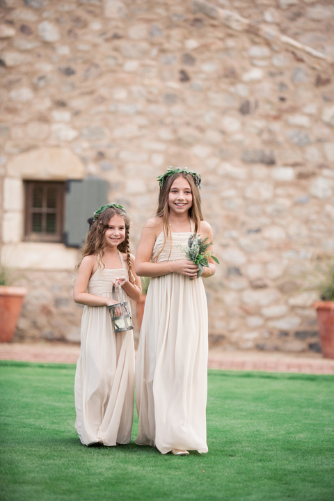 Flower girls in pale dresses with wreaths on their heads. Outdoor wedding ceremony