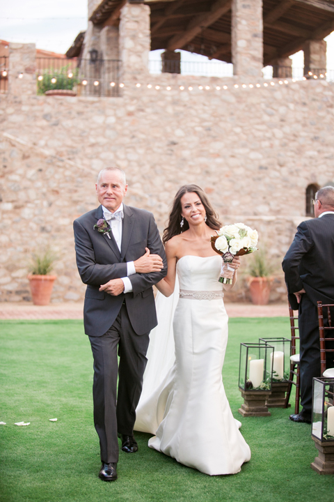 Father of the bride walks his glowing daughter down the aisle. Outdoor wedding ceremony