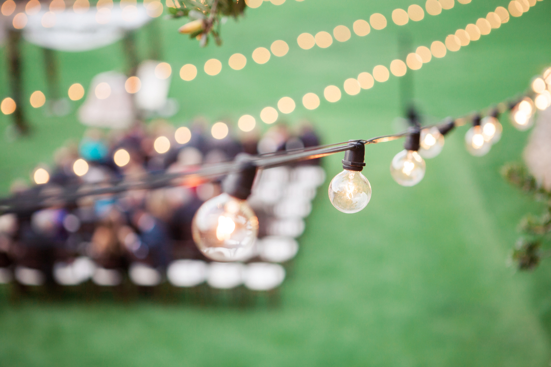 Globe lights strung above an outdoor wedding ceremony