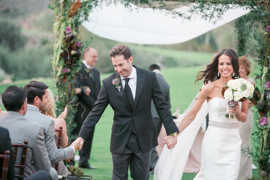 The groom accepts congratulations as he and his new walk walk back down the aisle