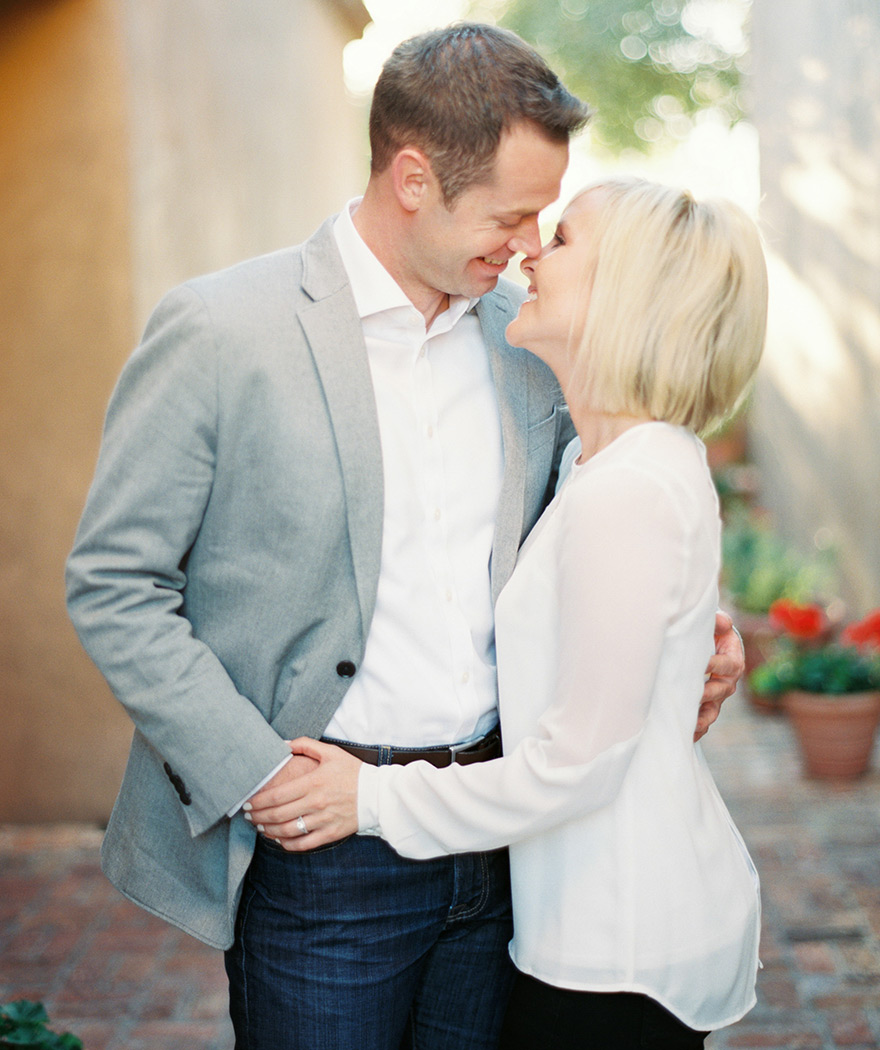 Couple leans in for a kiss as bride holds her groom 