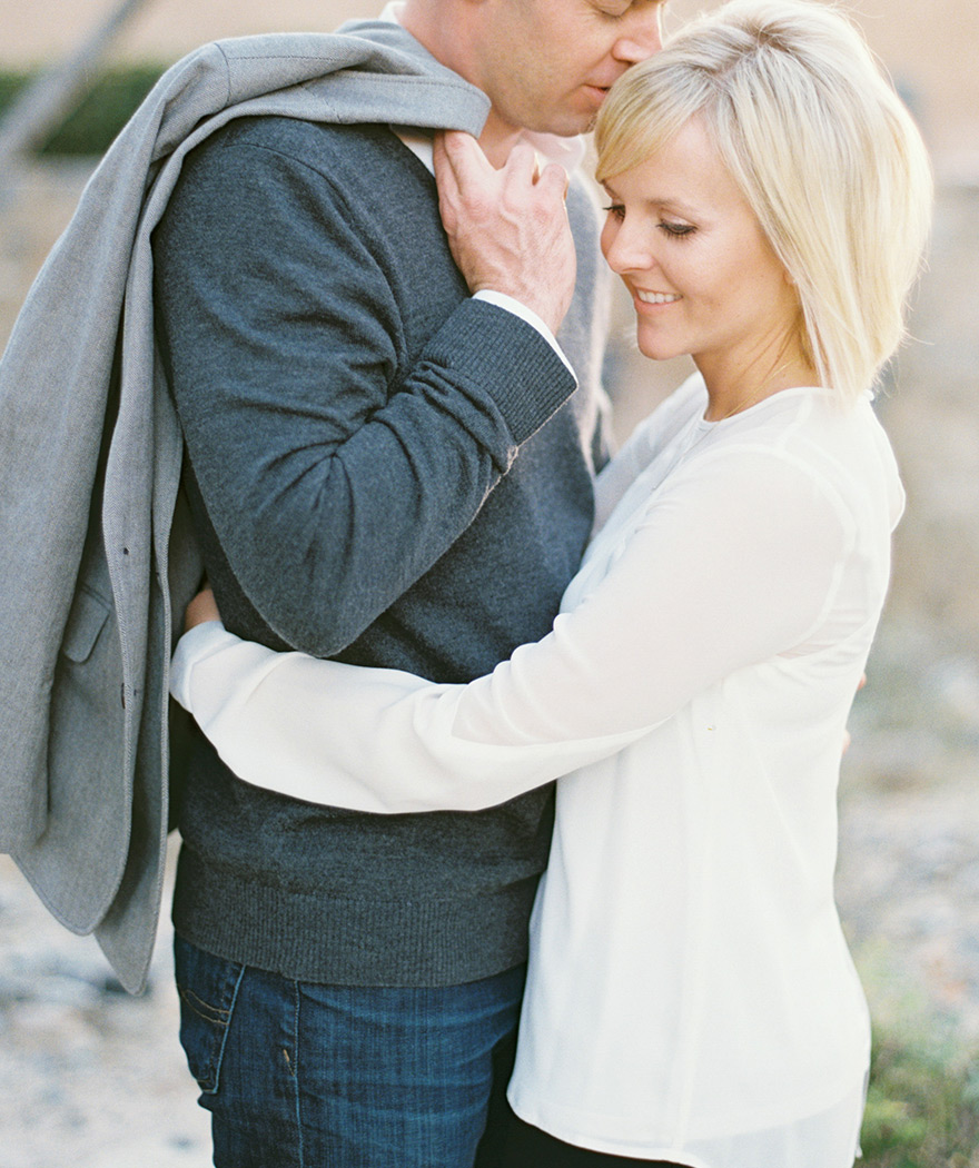 Relaxed close-up shoot of bride hugging groom as he leans in for affection 